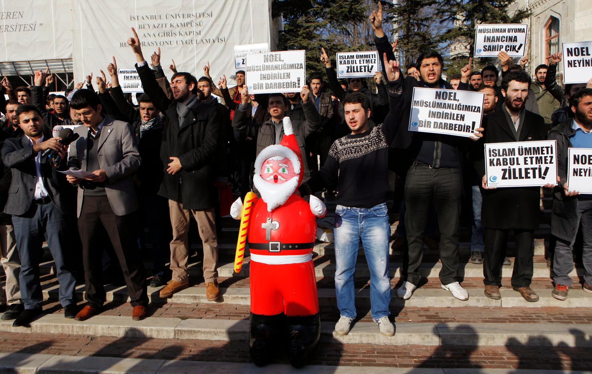 Turkish Islamist protesters shout slogans against Noel celebrations as they hold an inflatable Santa Claus toy during a demonstration at Beyazit Square in Istanbul December 26, 2013. The sign (front, 2nd) reads: "Christmas is a blow to our Islamism".