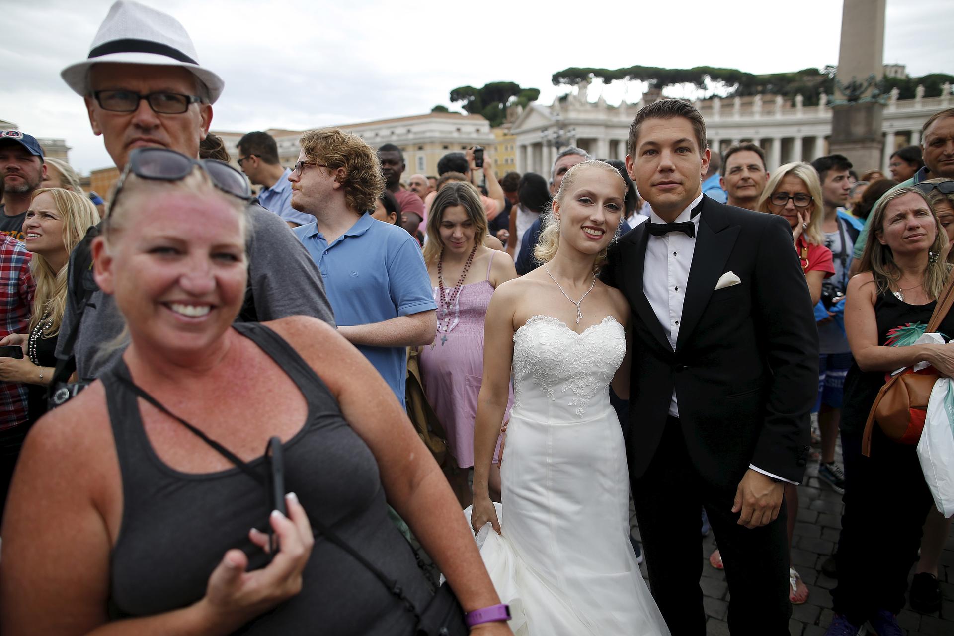 A newly wed couple attends as Pope Francis leads his Sunday Angelus prayer in Saint Peter's square at the Vatican, August 16, 2015.