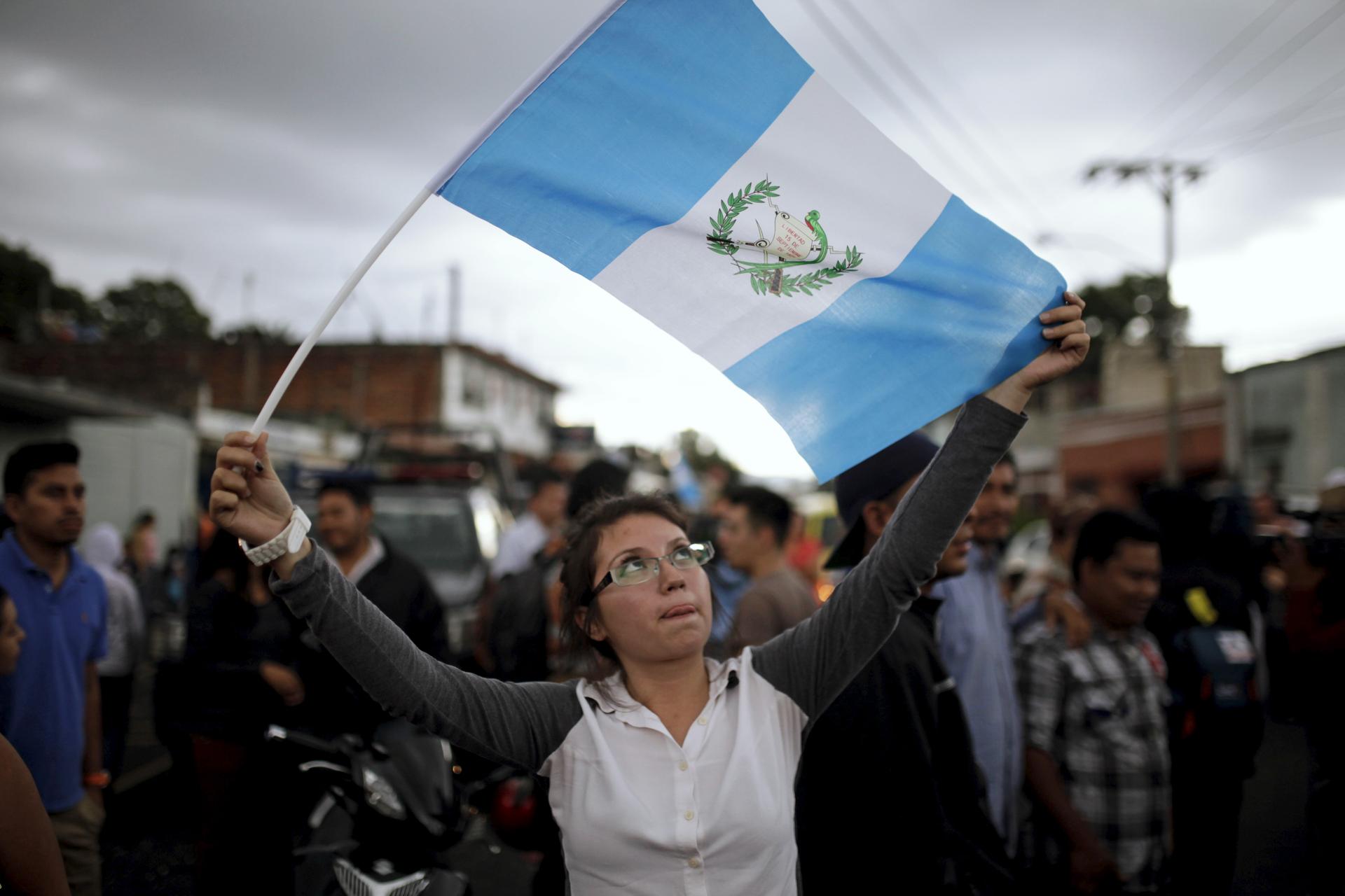 A woman holds a Guatemalan flag and celebrates as Guatemala's former President Otto Perez arrives at Matamoros Army Base, after a hearing at the Supreme Court of Justice, in Guatemala City, September 3, 2015.