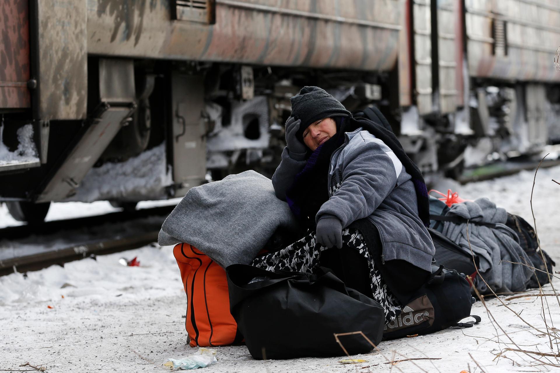 A migrant sits on her bags while waiting for a train in Presevo, Serbia.