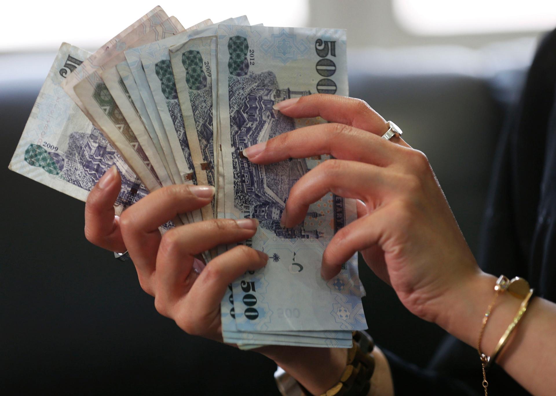 A Saudi woman shows Saudi riyal banknotes at a money exchange shop, in Riyadh, Saudi Arabia January 20, 2016.