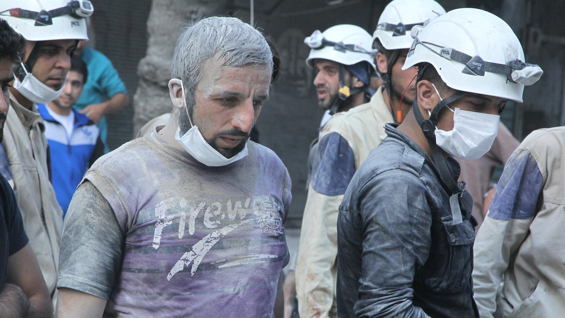 Residents and members of the Syrian Civil Defense, or "White Helmets," look for survivors at a damaged site after what activists said was a barrel bomb dropped by forces loyal to Syria's President Bashar al-Assad in the Al-Shaar neighborhood of Aleppo, Sy