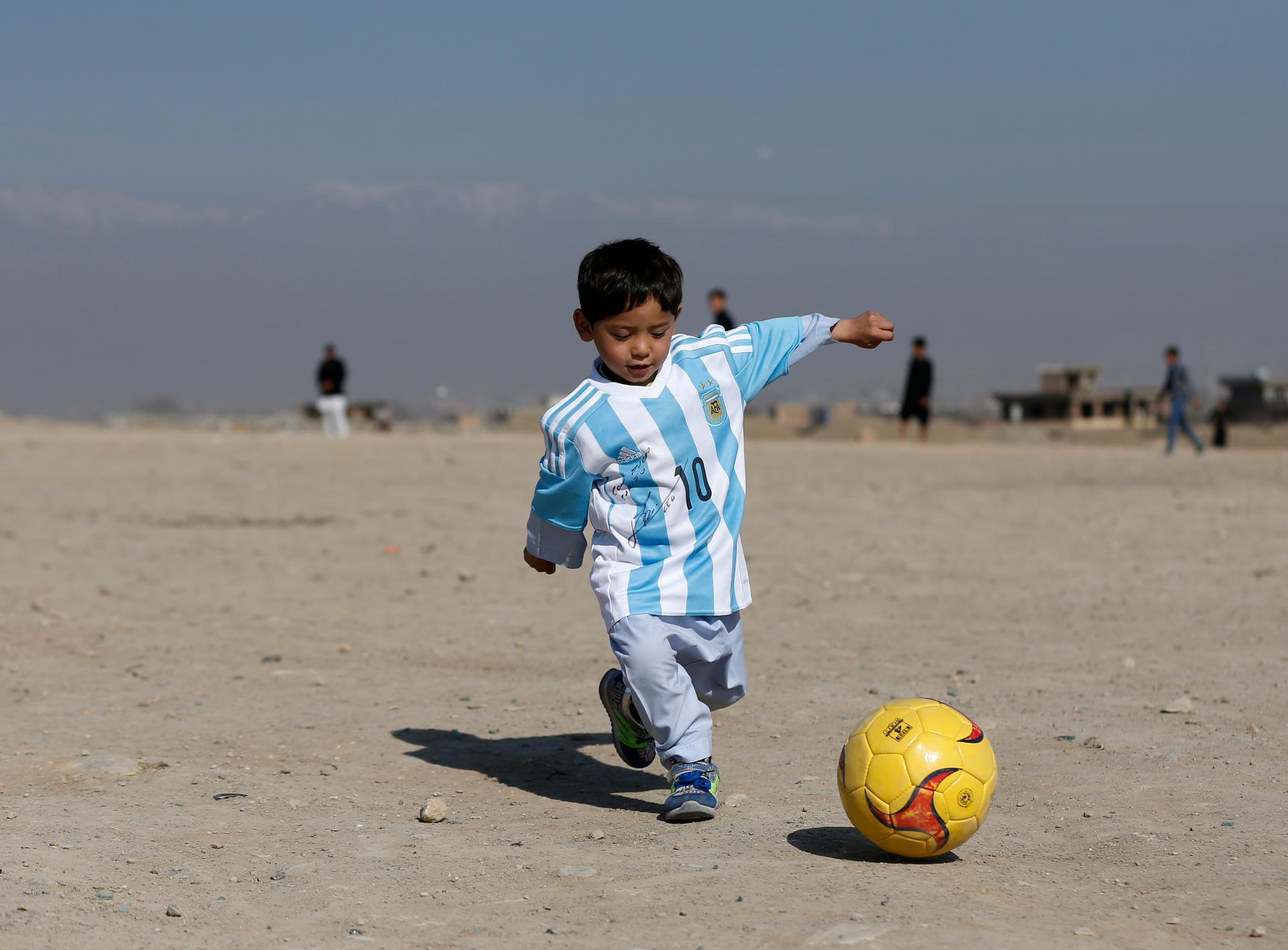 Five year-old Murtaza Ahmadi, an Afghan Lionel Messi fan, wears a shirt signed by Barcelona star Lionel Messi as he plays football at the open area in Kabul, Afghanistan February 26, 2016.