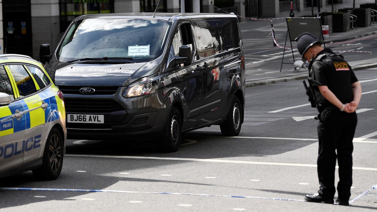 A City of London police officer bows in respect as a coroner's vehicle drives away from London Bridge, June 4 2017