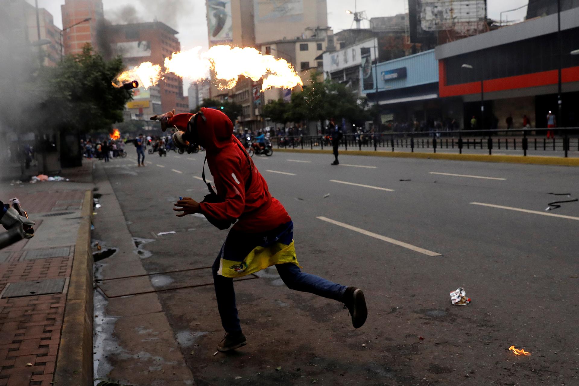 A demonstrator throws a petrol bomb during riots at a rally against Venezuelan President.