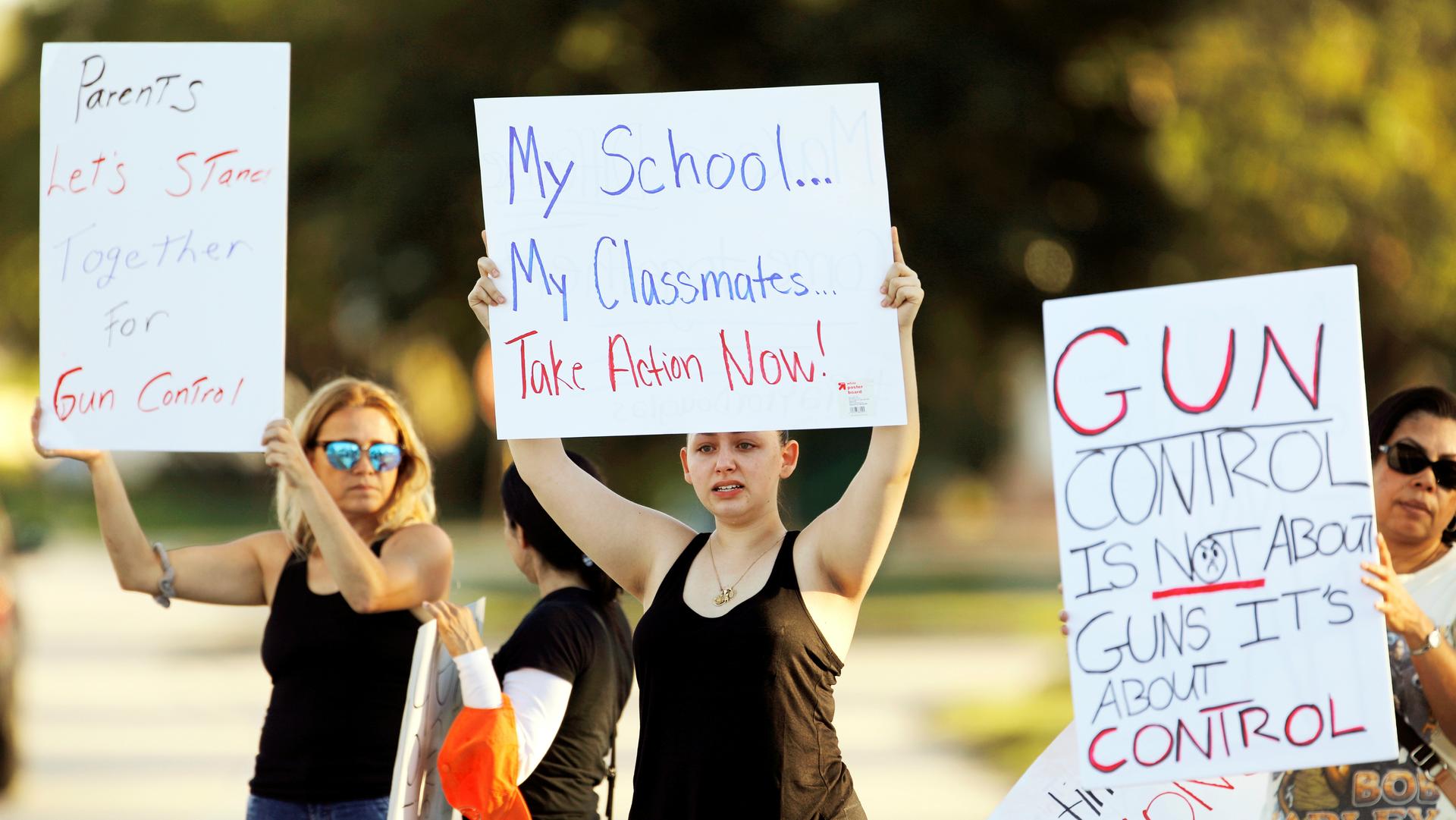 Angelina Lazo (C), an 18-year-old senior at Marjory Stoneman Douglas High School, lost two friends in the shooting at her school. She joined other gun control proponents with placards at a street corner in Coral Springs, Florida, on Feb. 16, 2018.