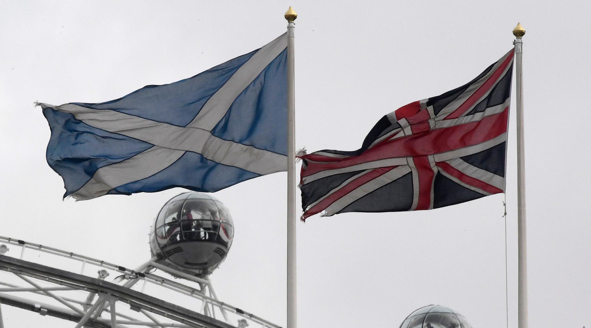 The British Union Flag, right, and a Scottish Saltire flag fly above the Scottish Office in Whitehall, with the London Eye wheel seen behind, in London.