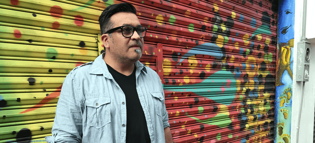 Robert Mendoza in front of a colorful mural