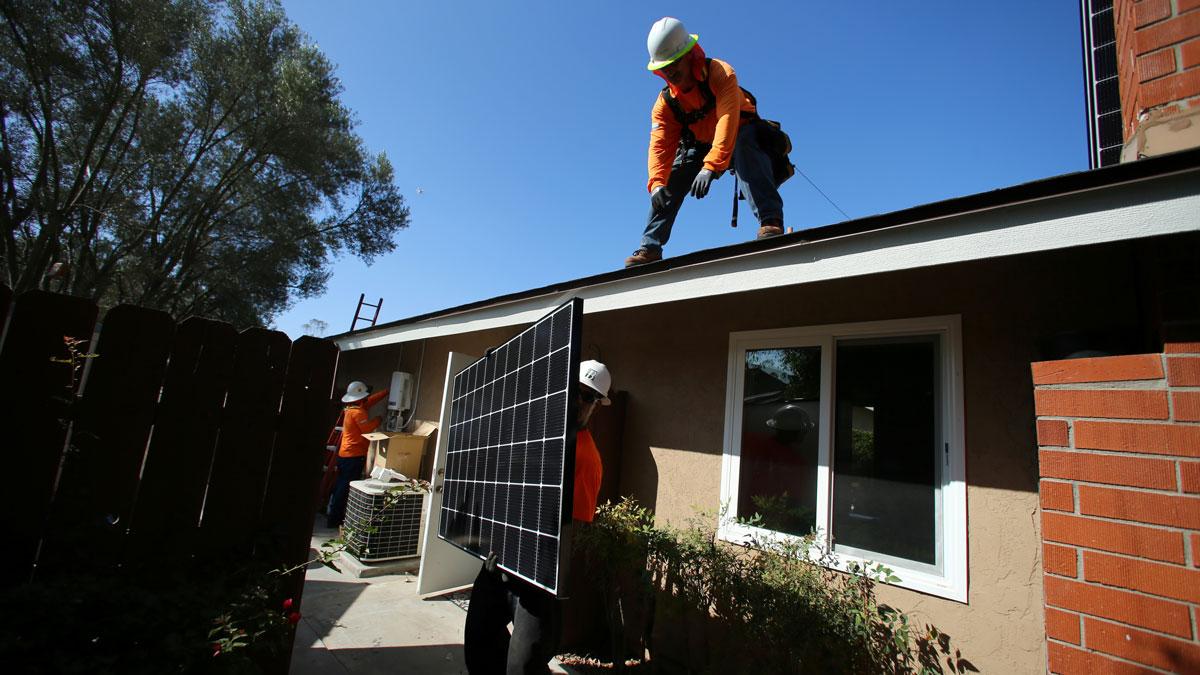 Tesla solar panels would replace the typical solar panel array, like this one being installed on home in Scripps Ranch, San Diego, California. Elon Musk wants to merge the two companies.