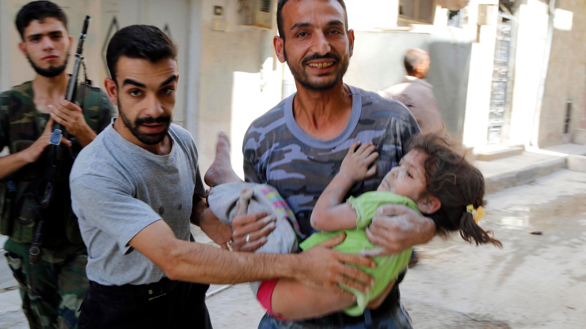 A man reacts as he carries a child who survived what activists said were barrel bombs dropped by forces of Syria's President Bashar Al-Assad in the Al-Fardous neighborhood of Aleppo, September 19, 2014.