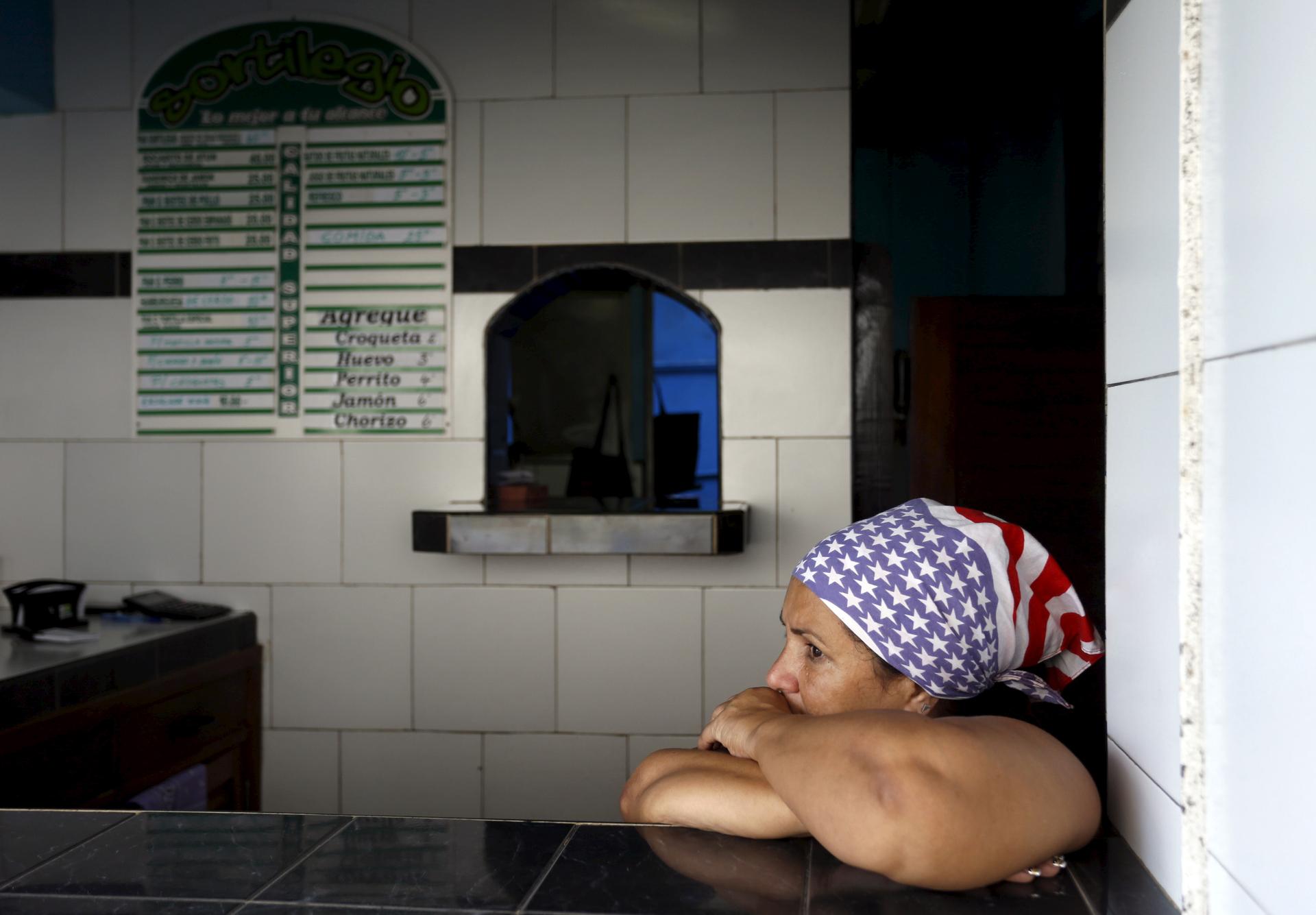 A Cuban woman waits for costumers in her private cafeteria, while wearing a scarf with the colors of the US flag, in Havana April 11, 2015.