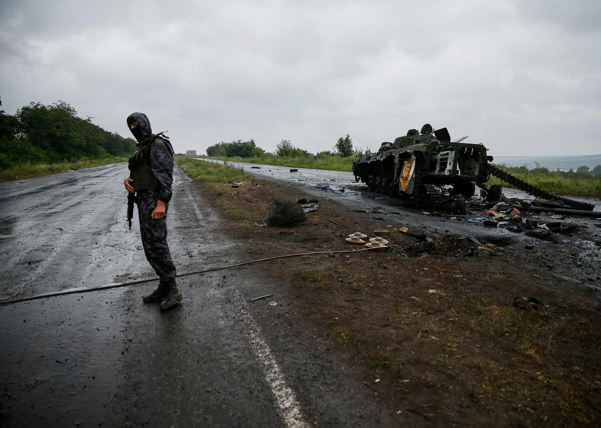 A Ukrainian soldier stands near a destroyed military vehicle of pro-Russian separatists just outside the eastern Ukrainian town of Slaviansk, July 7, 2014. REUTERS/Gleb Garanich