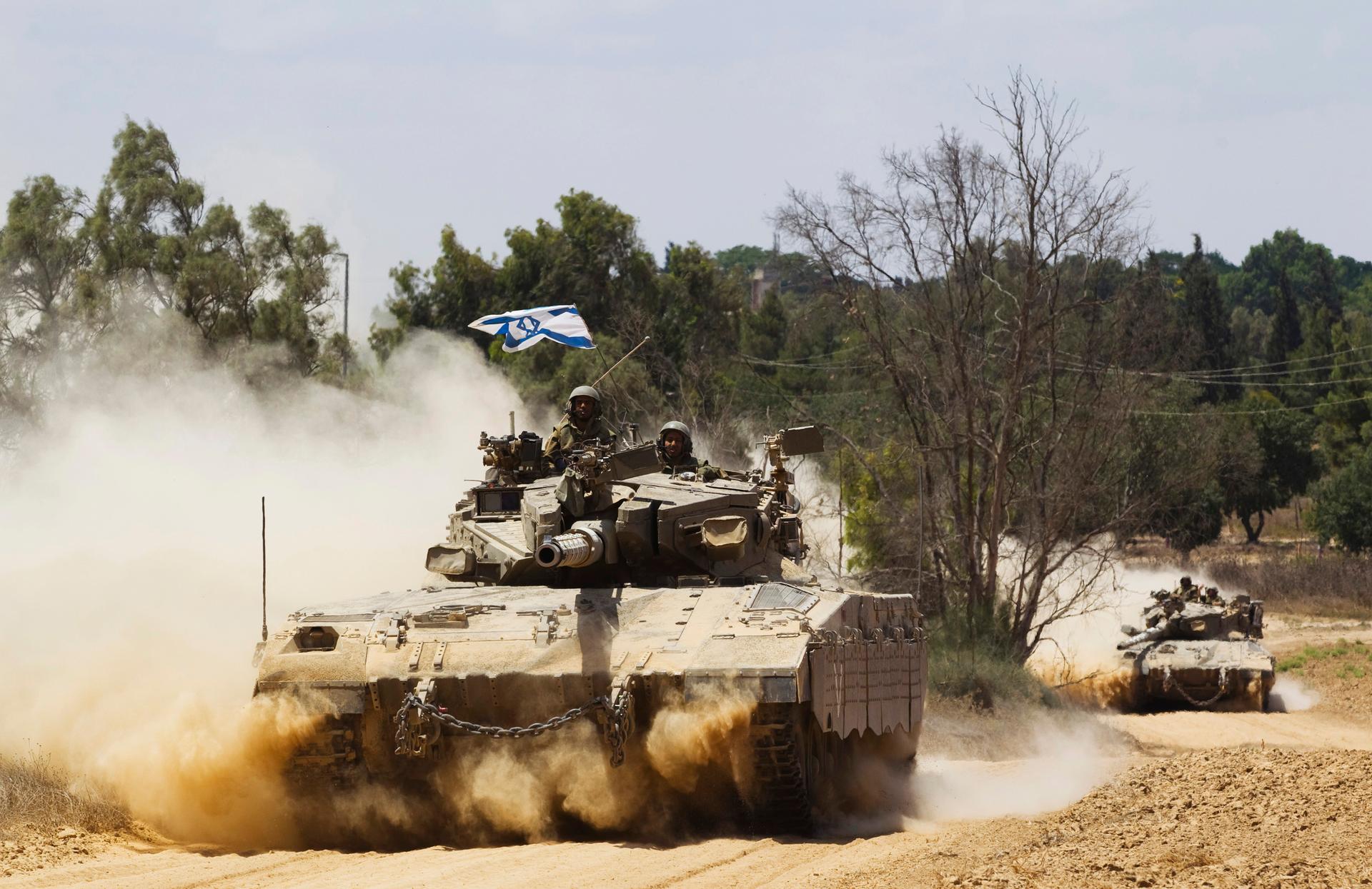 Israeli soldiers travel atop tanks outside the Gaza Strip July 18, 2014. Israel stepped up its land offensive in Gaza with artillery, tanks and gunboats on Friday and declared it could "significantly widen" an operation Palestinian officials said was kill