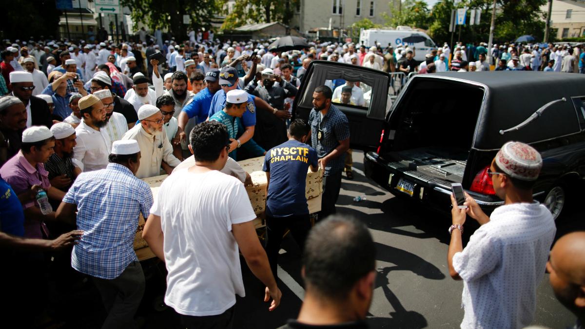 A crowd of community members move the coffin of Imam Akonjee