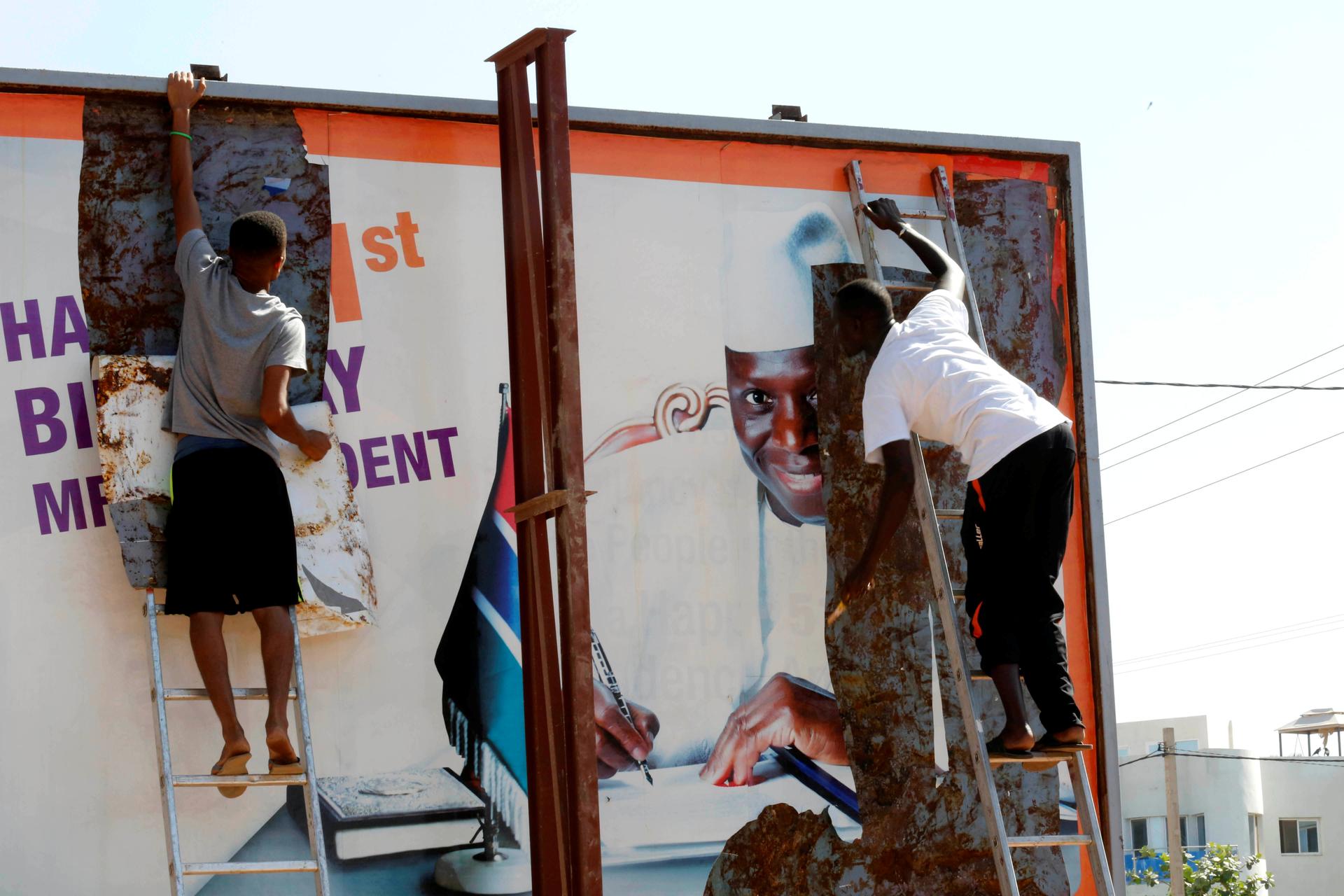 People tear a poster of former Gambian president Yaya Jammeh in Broussbi, Gambia, December 4, 2016.