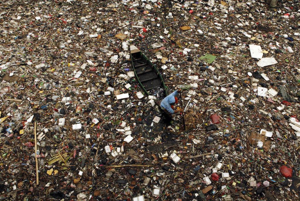 A scavenger collects plastic for recycling in a river covered with rubbish in Jakarta, Indonesia, April 20, 2009.
