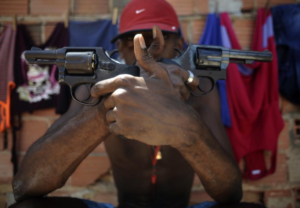 A Brazilian drug gang member nicknamed Pilintra, 26, poses with guns in Salvador.