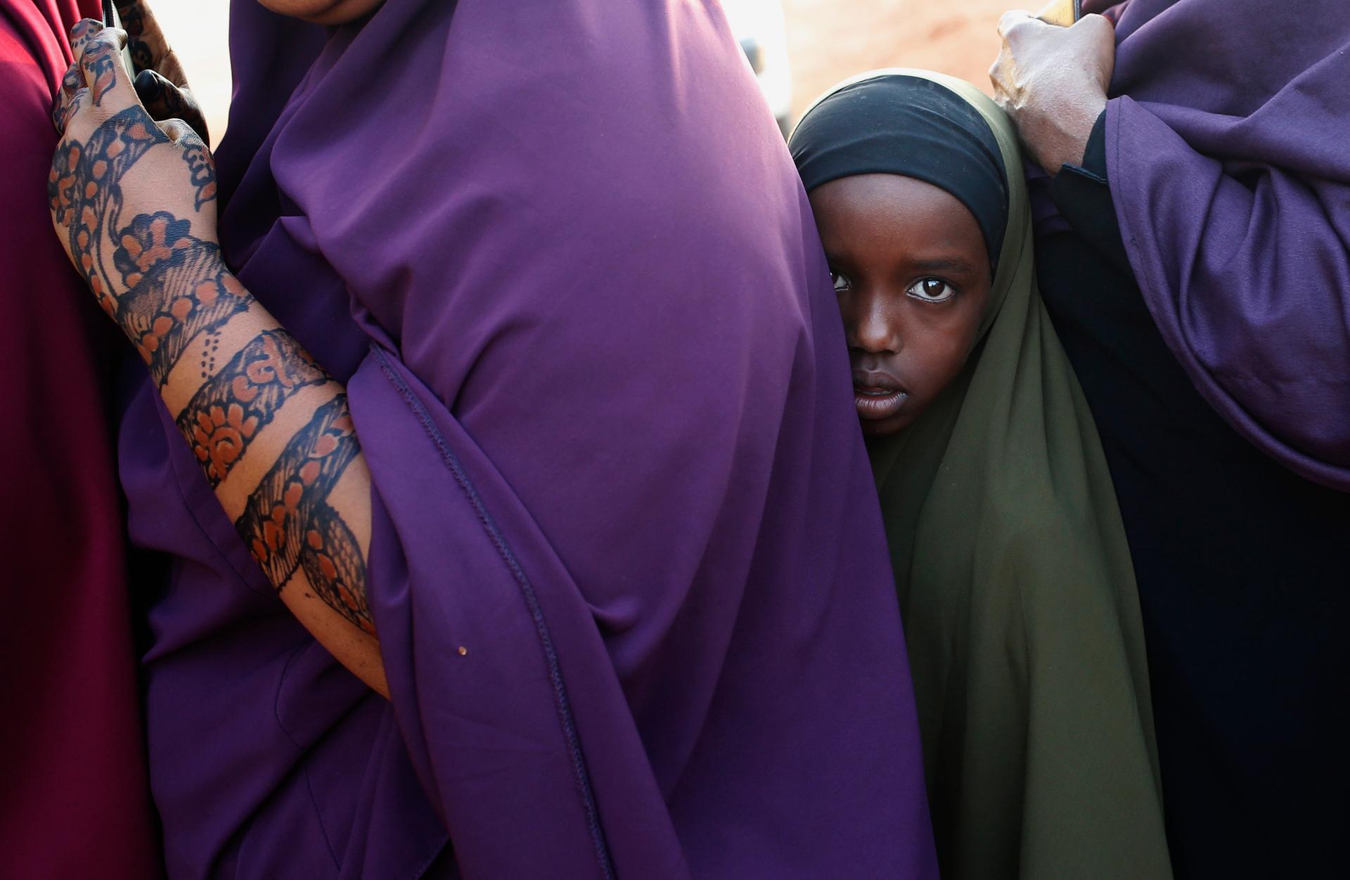 A girl stands in line in front of a bus with other passengers traveling to Nairobi.  They are in the town of Mandera at the Kenya-Somalia border where terrorist group al-Shabab has launched attacks against non-Muslims.