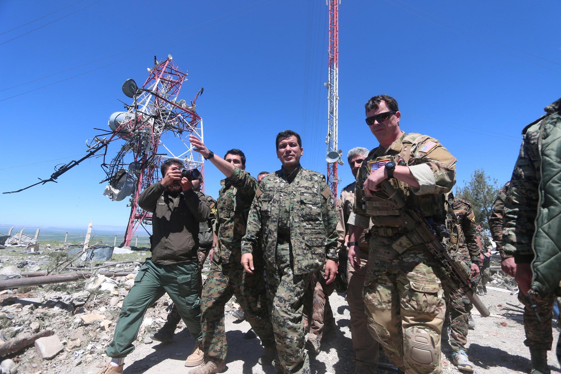 A US military commander, right, walks with a commander from the Kurdish People's Protection Units