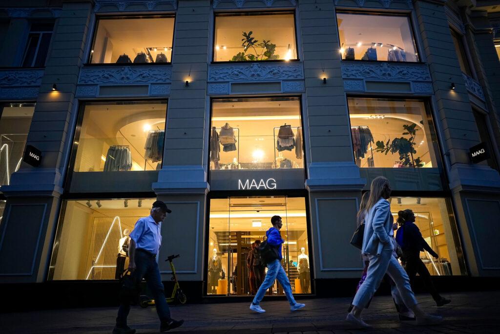 Люди проходят ночью мимо недавно открывшегося магазина Maag, бывшего флагманского магазина Zara. 