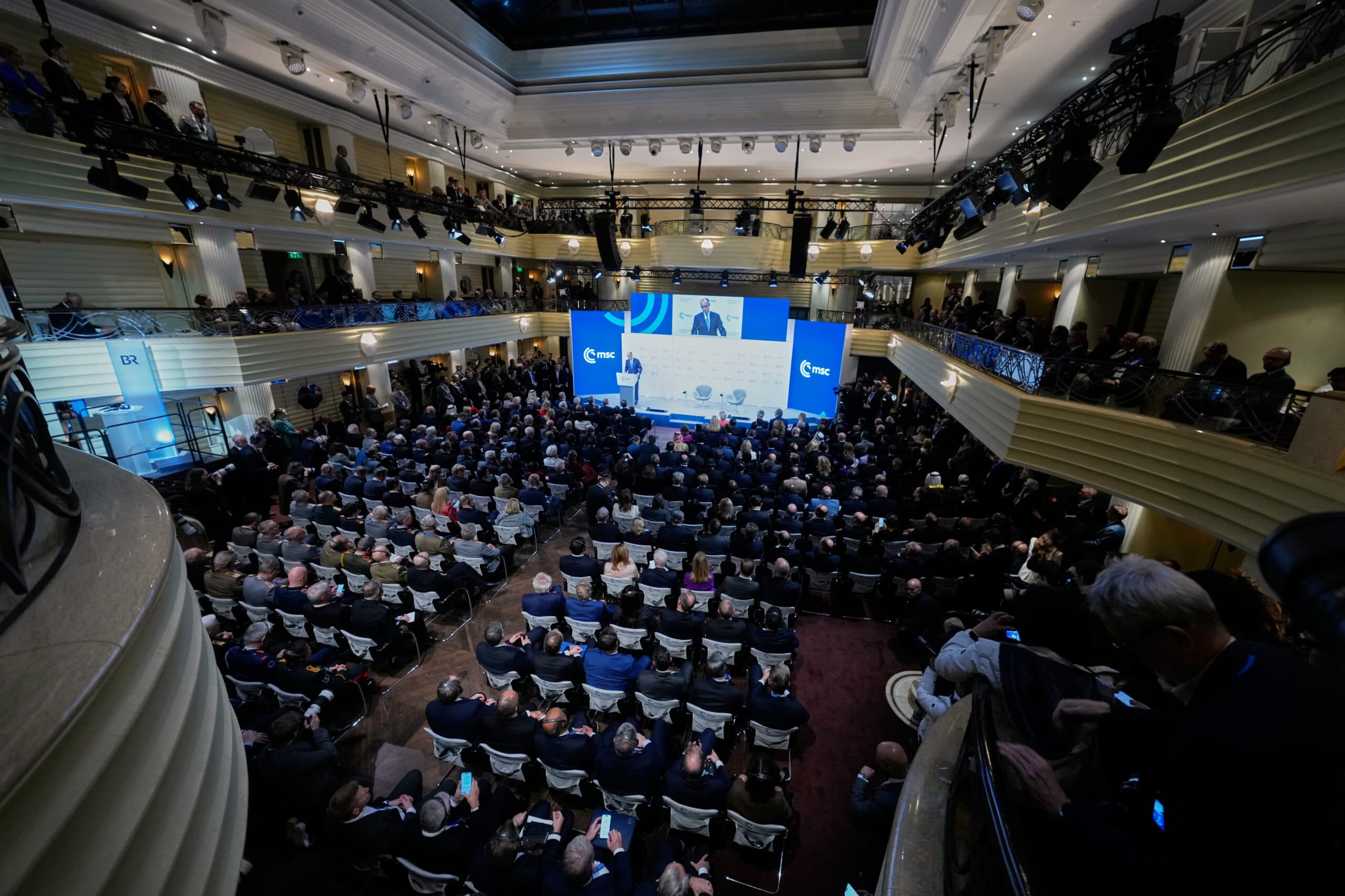 A large audience is gathered in a multi-tiered conference hall with a speaker addressing them from a stage with the 'msc' logo displayed prominently.