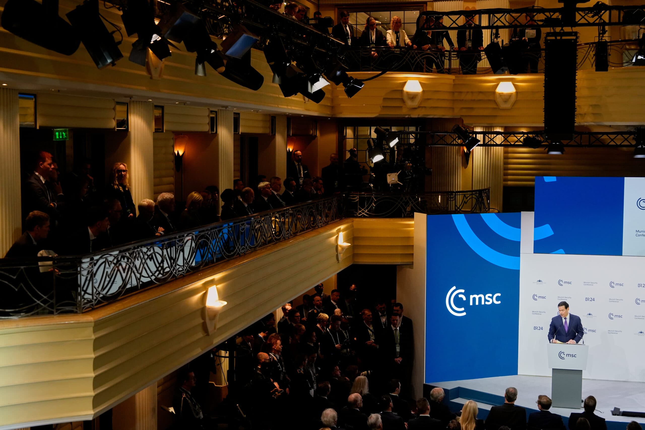 A large conference room filled with people listening to a speaker at a podium on stage during an event, with 'msc' logos displayed on screens and walls.