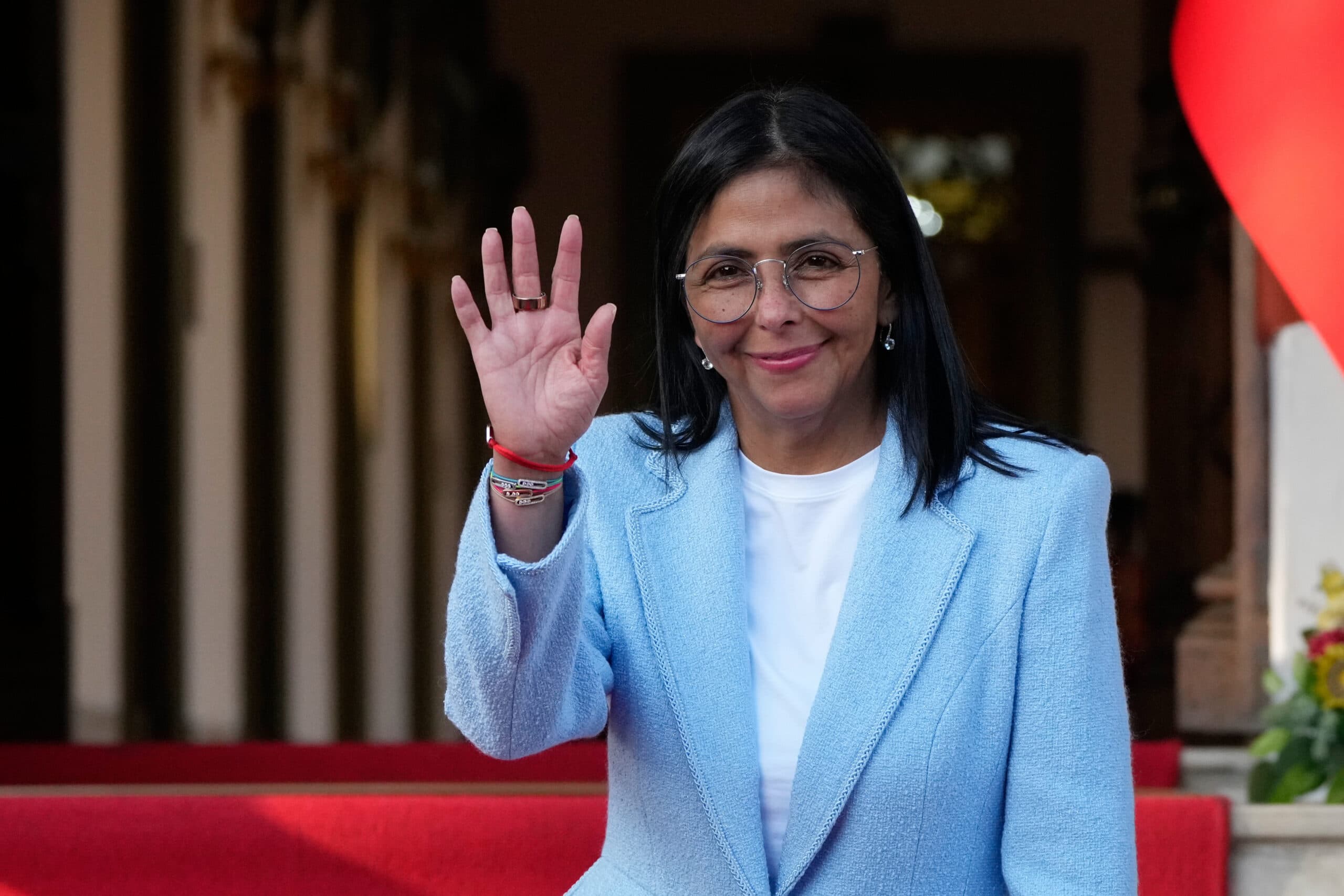woman in a blue suit waves and smiles