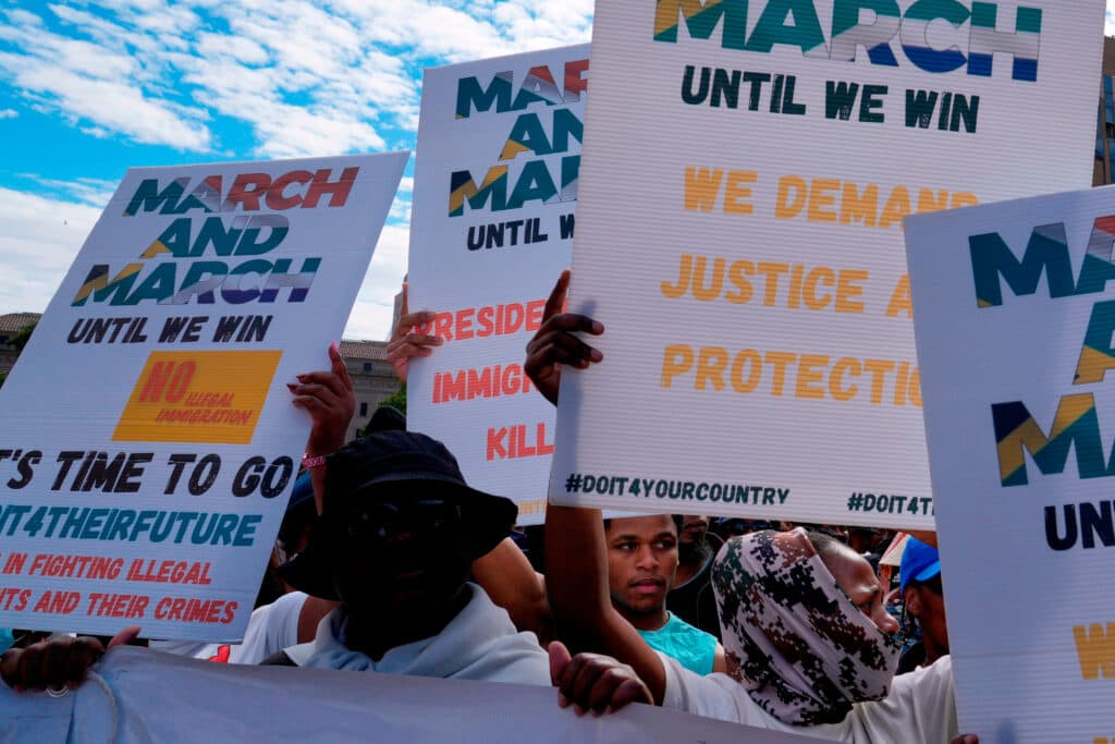 People holding protest signs with messages about justice, immigration, and unity.