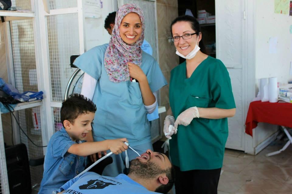 Mohammad, a boy Farris Barakat (seated) helped in the Project Refugee Smiles clinic, says he wants to be a doctor when he grows up. Standing next to him are Dr. Sara Aref of Cleveland (center) and Alena Advic of Seattle.