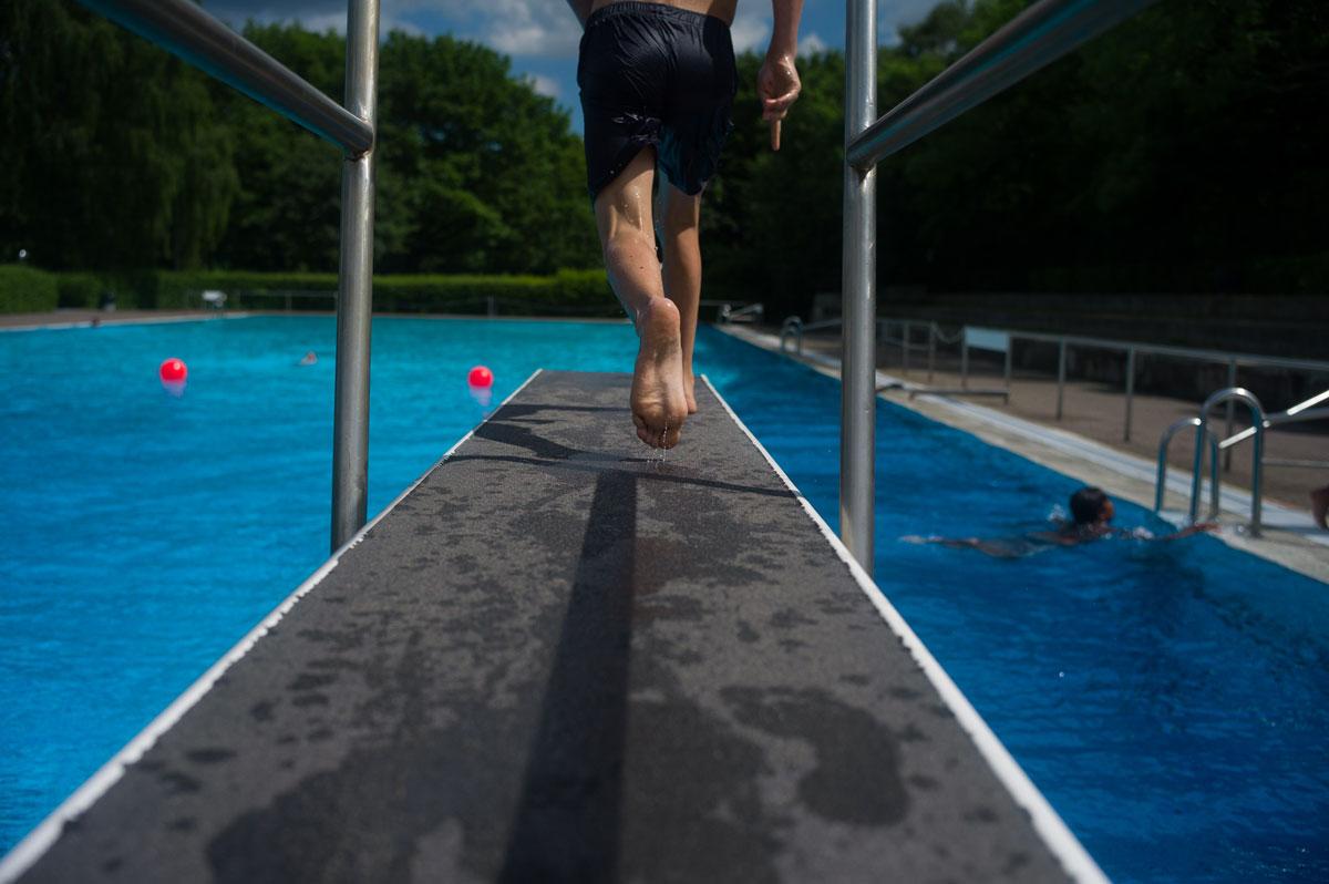 A young swimmer takes a running leap off of a diving board at Sommerbad Neukolln.
