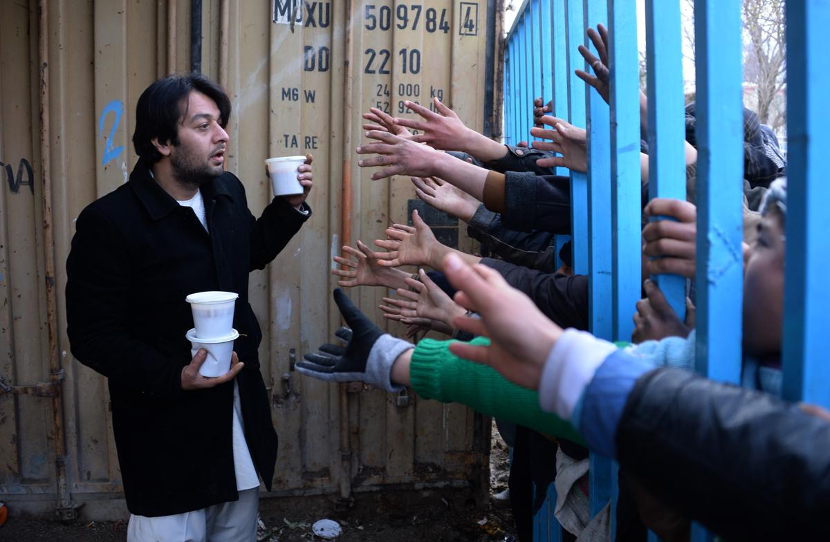 Men and children reach out for food donated by a charity in Mazar-i-Sharif in January 2015.