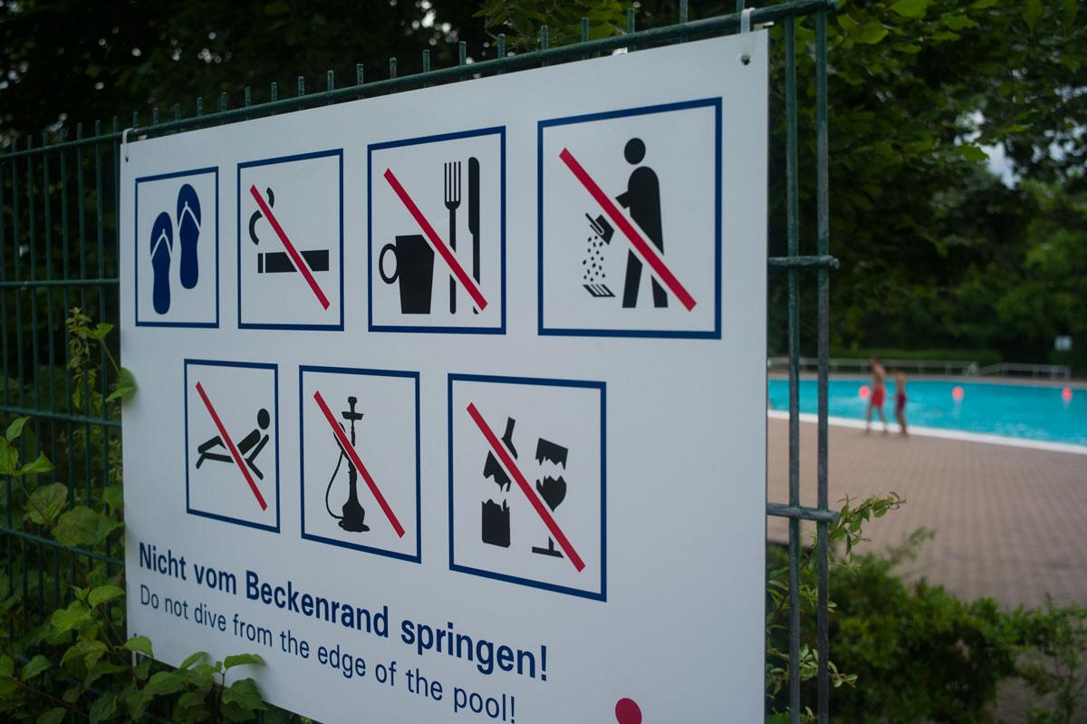 A sign just beyond the edge of the wading pool at the Sommerbad Neukolln advises guests to wear sandals and that the smoking of hookahs is prohibited. It is common in Middle Eastern cultures to smoke hookah while relaxing in the warm weather, but due to t