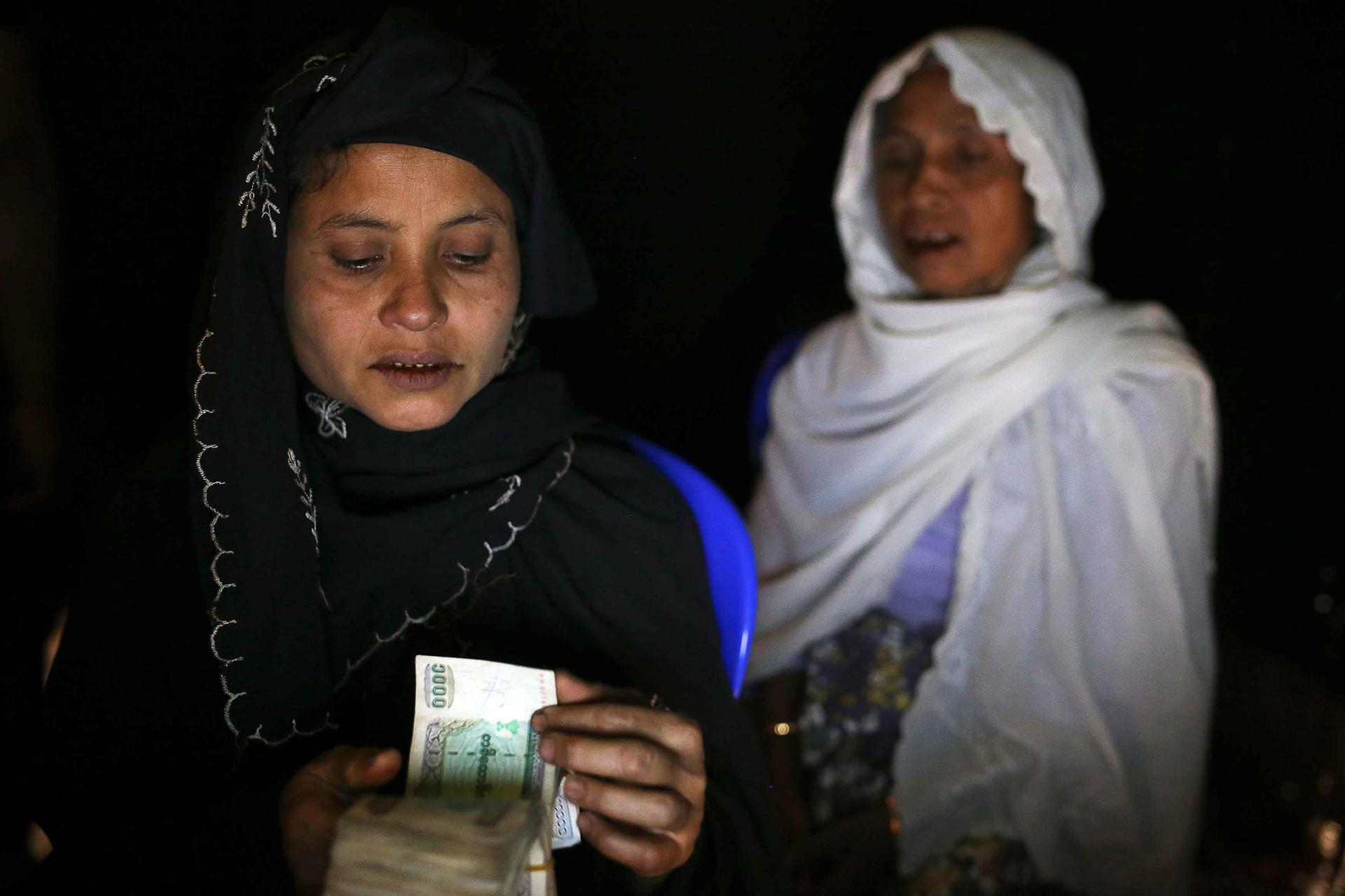 Jeweliyar, a 35-year-old Rohingya, counts out about $600 worth of Myanmar currency while her mother Toryubar, 65, watches on in an Internet hut. The money is part of a $1,500 ransom demanded for Toryubar's 23-year-old daughter, who is held by traffickers