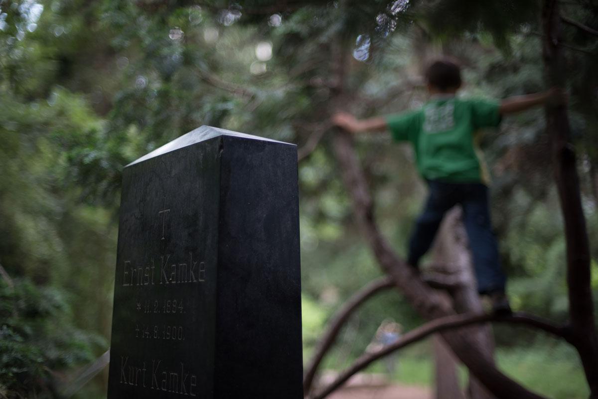 A young guest climbs a tree near a headstone in Berlin’s Leise Park, a former cemetery in Berlin, Germany’s hip neighborhood of Prenzlauerberg. The children in the park all report having favorite headstones and trees in the small, walled-off garden park.