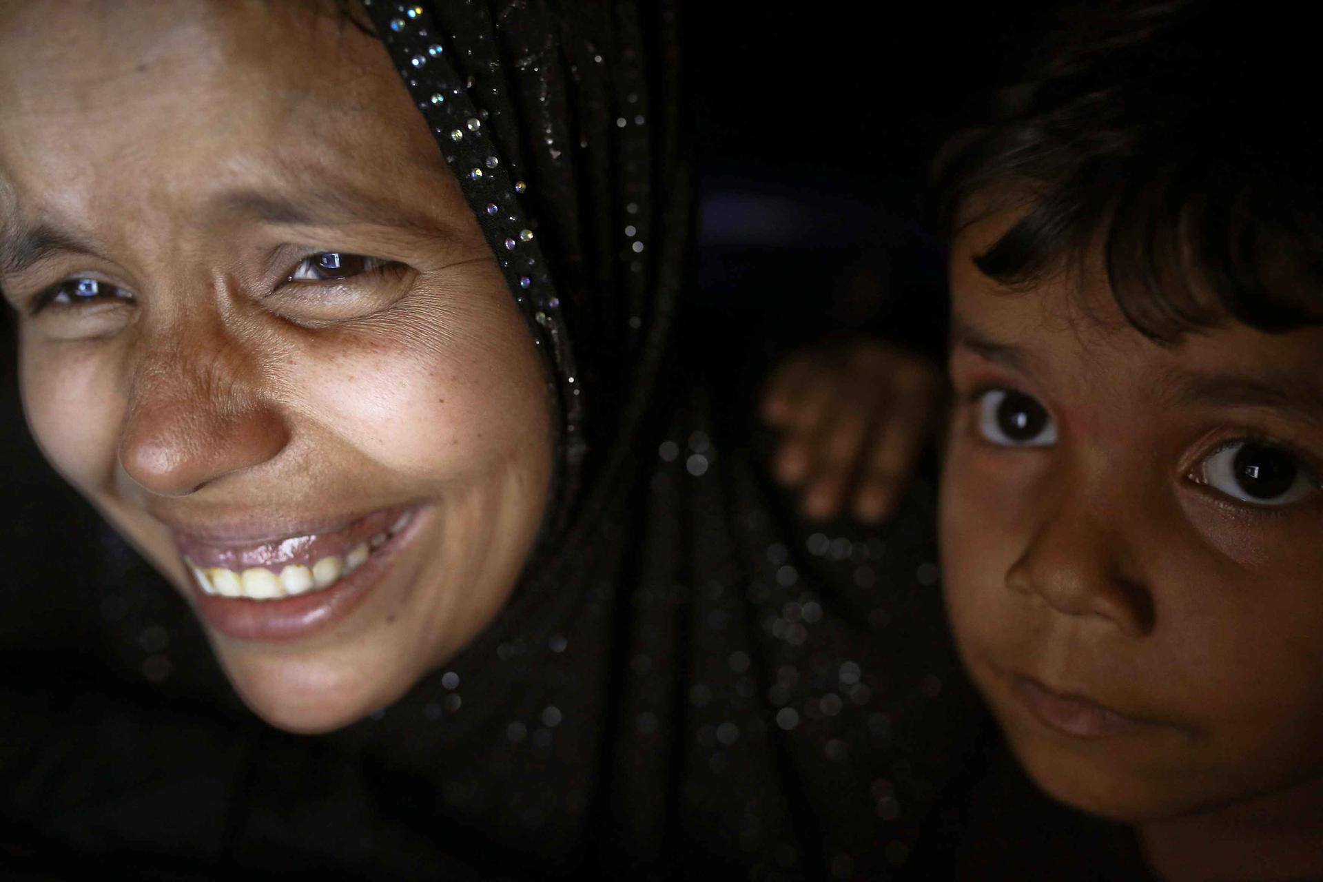 Noor, a 28-year-old Rohingya woman, jokes with her husband Muhammad Rafiq, 35, while their son Noor Kaidar listens. Rafiq has been working in Malaysia for 10 months; this is the fifth time they've spoken during that period. 