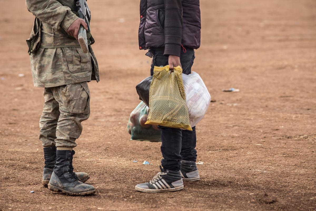 A Turkish policeman stops a man trying to bring food to the border in order to help the people under siege across the border in Kobane, Syria. Several thousand civilians are believed to still be in the town after more than 100,000 fled over the past two w