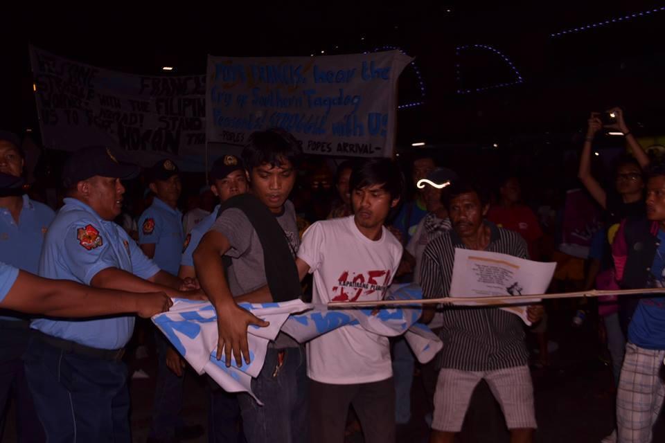 Members of the Philippine police confiscate an activist's banner. The police said only 
