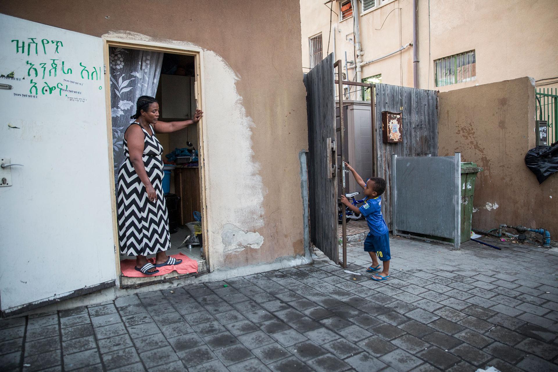 Tariki Gebru, 4, speaks with a neighbor, Ethiopian-Israeli Mazal Kfyalew. She immigrated to Israel in the 1990s and sells the traditional flatbread ingera, which she oftentimes brings to Gebru and her sons. She says she pities them living in such difficul