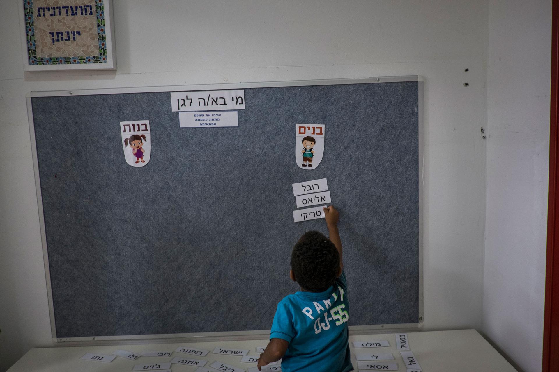 Tariki Gebru, 4, who attends a kindergarten provided by the Tel Aviv municipality catering to immigrant children, completes his first task of the day. He struggles but finally finds his name in Hebrew from a stack of names and places it in the 