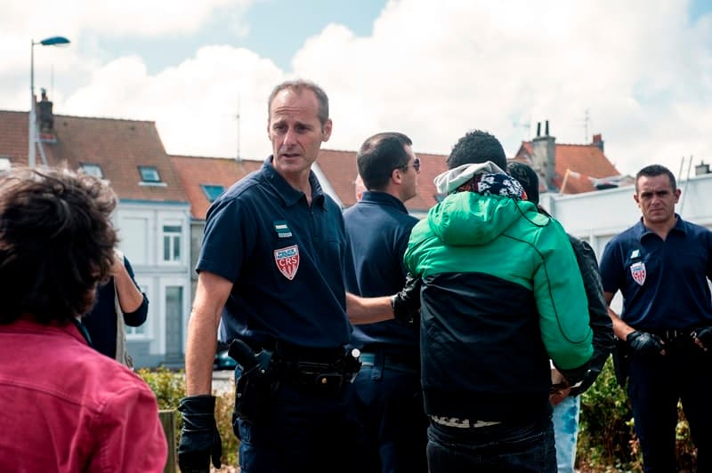 A policeman catches a young refugee who had just received a meal. He must leave the area without eating, July 25, 2017.