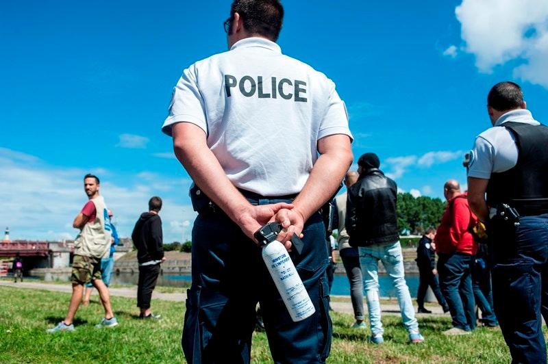 A policeman holding pepper spray keeps the refugees and volunteers from leaving the perimeter. Police stop the supply of meals for refugees and carry out identity checks, July 25, 2017.