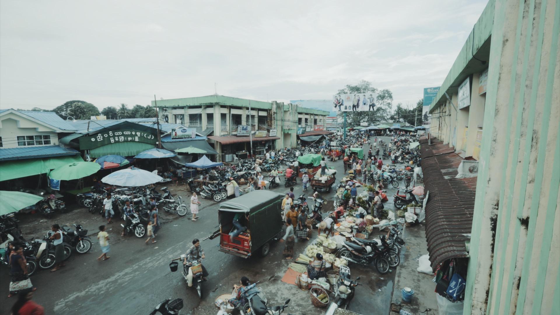 A bustling market in Myitkyina, Myanmar, the last outpost in the country's northern frontier before the region disintegrates into a lawless zone ruled by militias. Myitkyina contains the northernmost terminal station on a rail line built during British co
