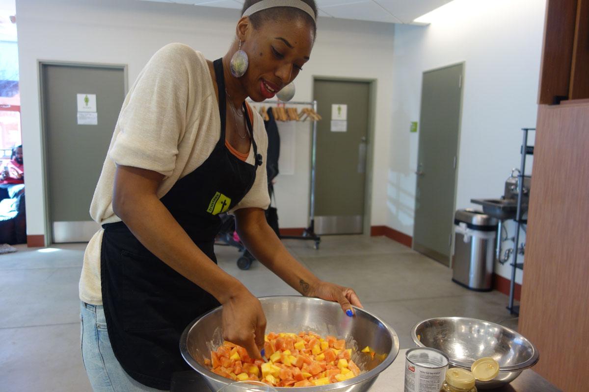 A student stirs up a mango and papaya fruit salad--a West African dessert with bits of coconut, peanuts and honey.