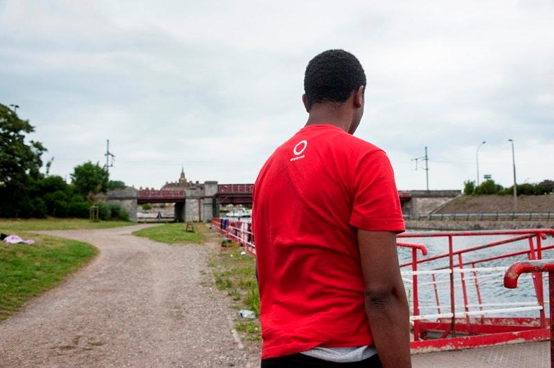Hussen, a 20-year-old Oromo refugee, stands in front of the canal in Calais where he fell during a police check, July 26, 2017.