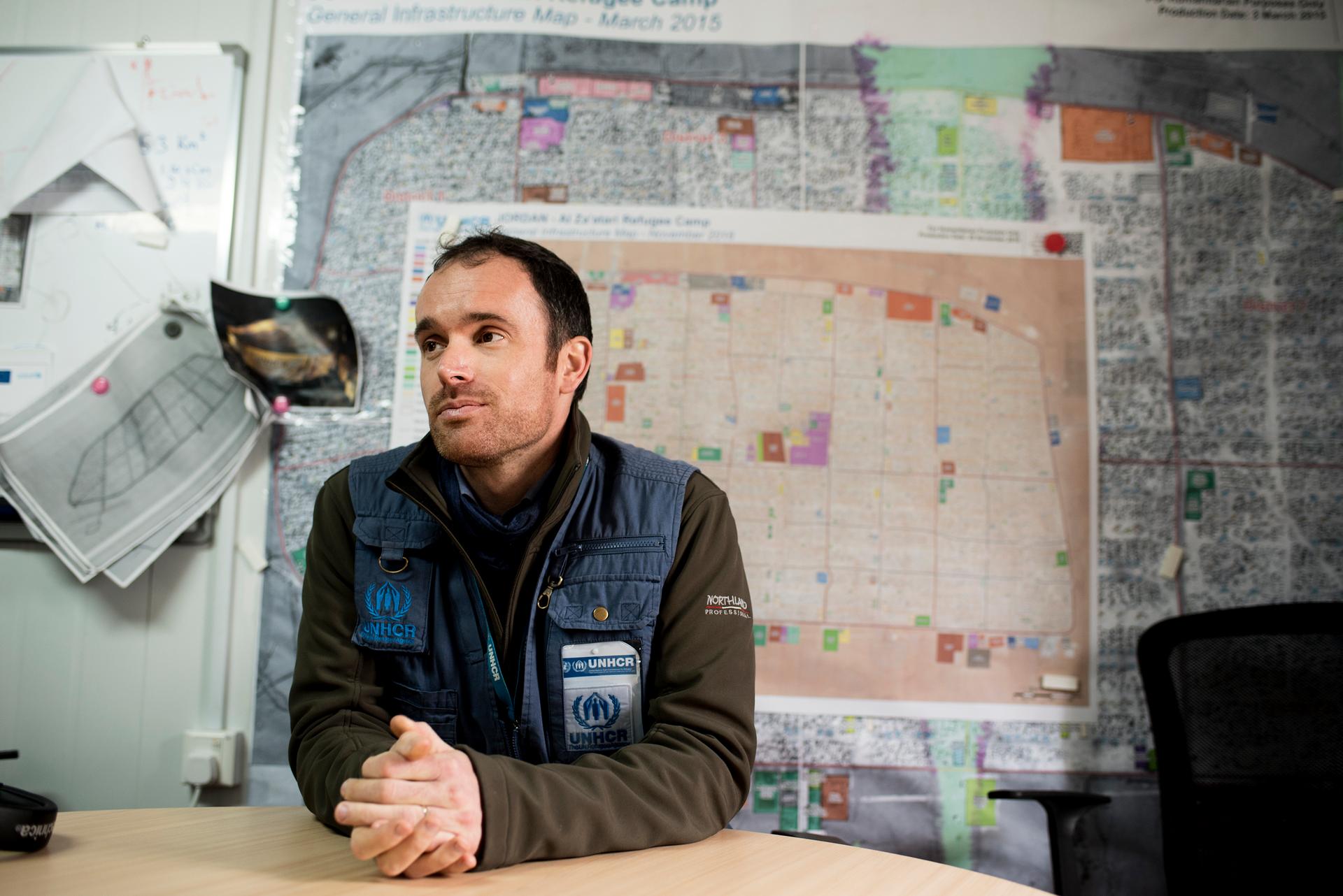 Gavin White, UNHCR External Relations Officer, sits in front of maps of the camp's sprawl at the UN refugee agency's Zaatari camp headquarters.