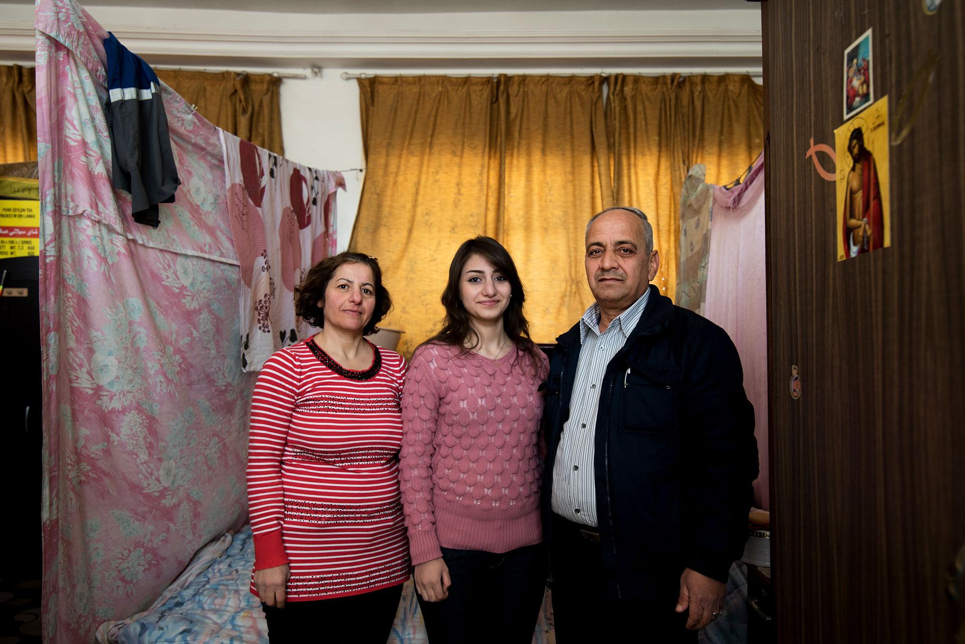 Mosul residents Shatha Gabrail, 50, and Numair Faisal Elyas, 56, pose with their daughter Merna in the curtained-off space in the St. Mary's Church where they've lived for over two years.