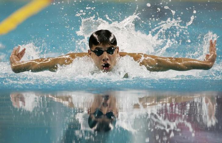 Syrian swimmer Rami Anis, wearing goggles but no swimmer's cap, emerges above the water during a butterfly stroke