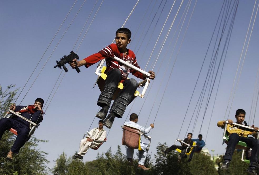 An Afghan boy holds a toy gun as he enjoys a ride with others on a merry-go-round to celebrate the Eid al-Fitr festival on Sept. 20, 2009, in Kabul.