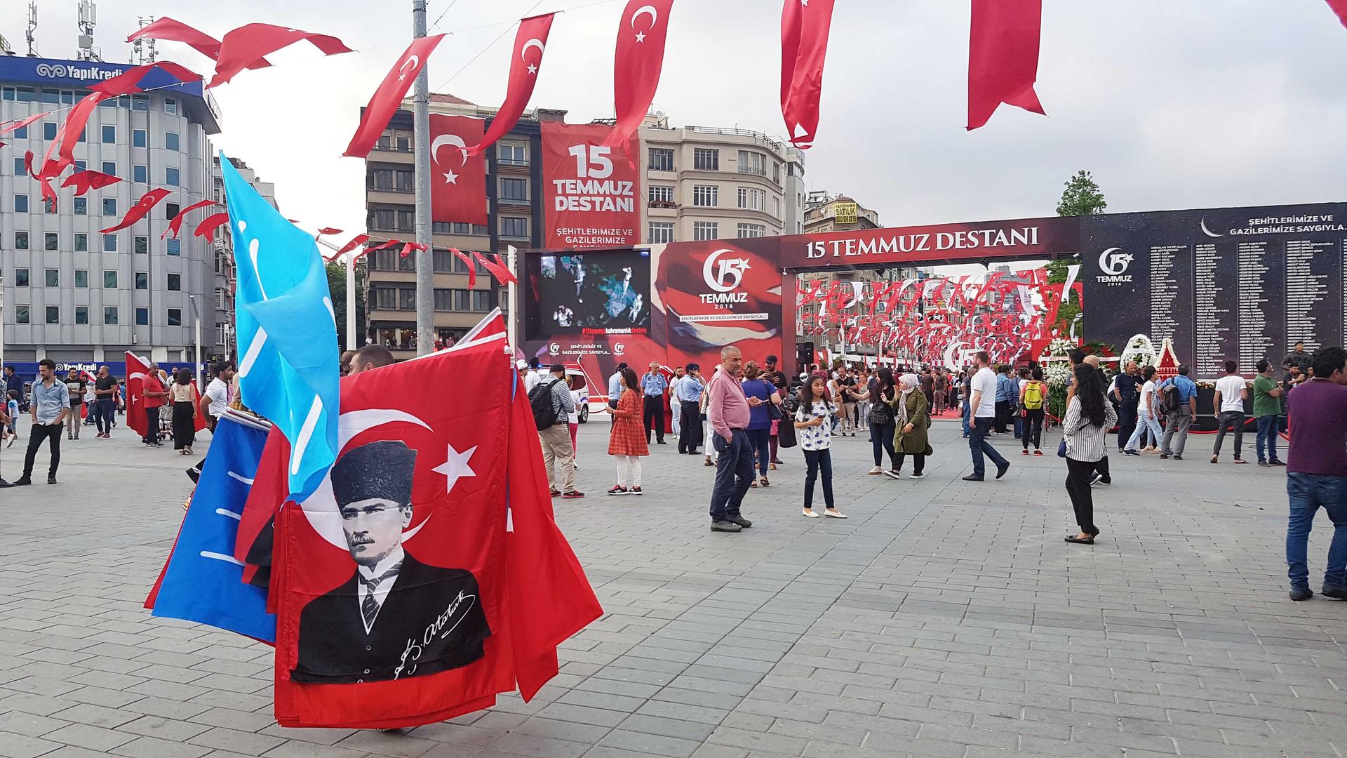 A vendor holding a Mustafa Kemal Atatürk flag walks outside the July 15 memorial area set up in Istanbul's Taksim Square.