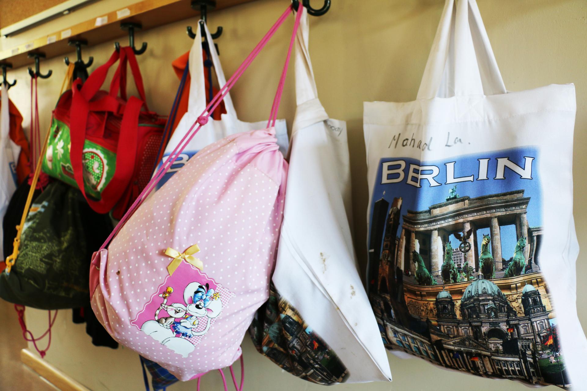 A row of colorful bags hangs on the back wall of the classroom.